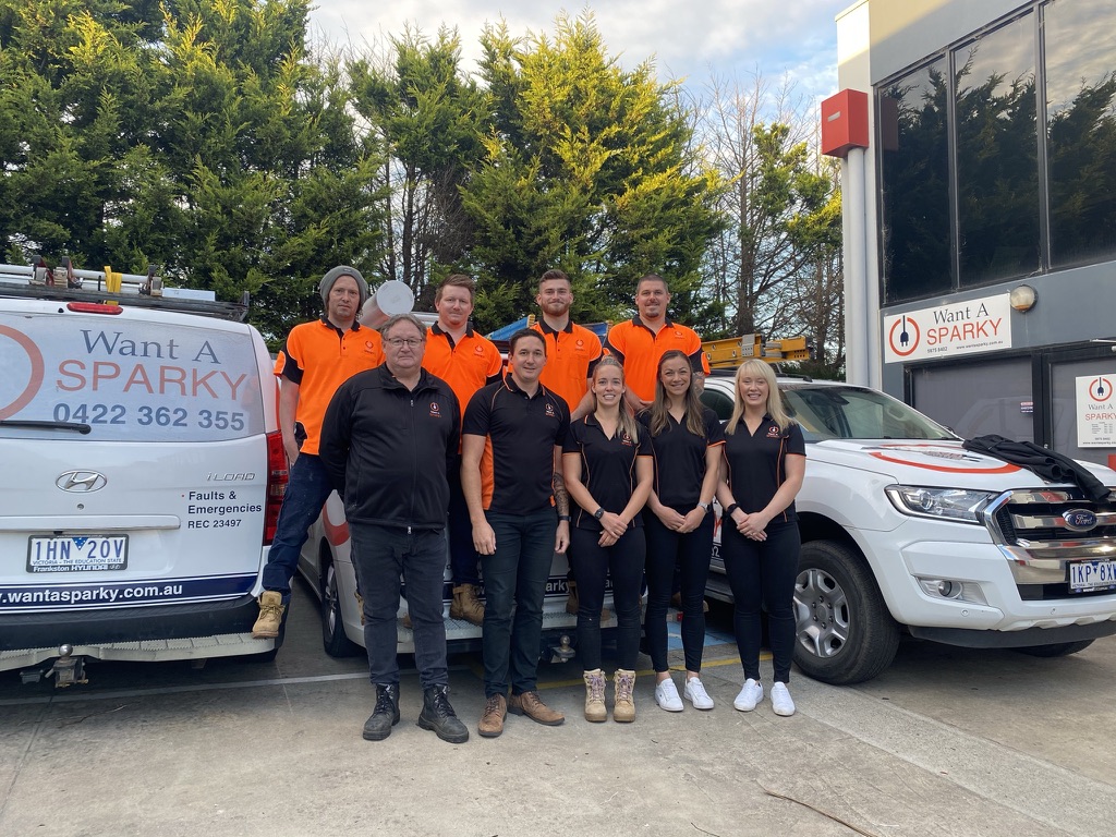 Want A Sparky team standing beside company vehicles